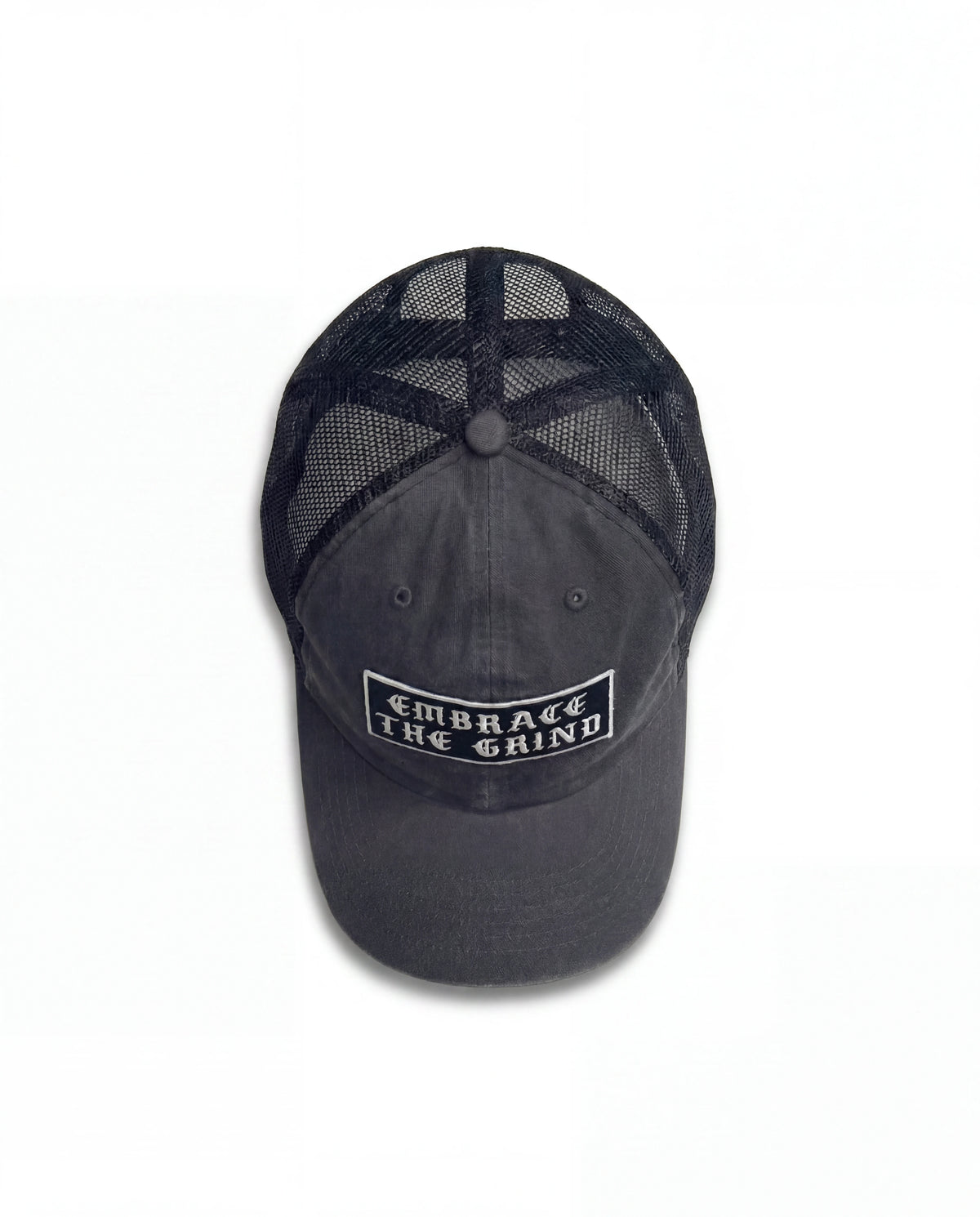 Black washed trucker hat with embroidered Embrace The Grind patch — front view